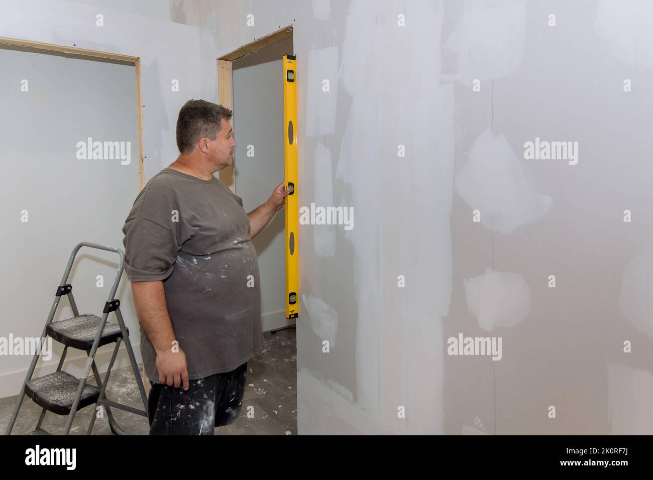 L'employé vérifie l'égalité d'un mur de cloison sèche avant de peindre Banque D'Images