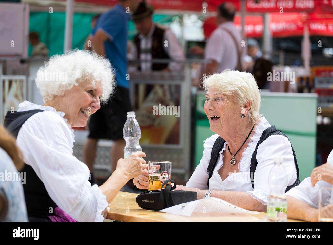 Les femmes en costume de Tirol ont beaucoup de plaisir tout en prenant un verre sur la terrasse extérieure à Zell am See, Autriche Banque D'Images