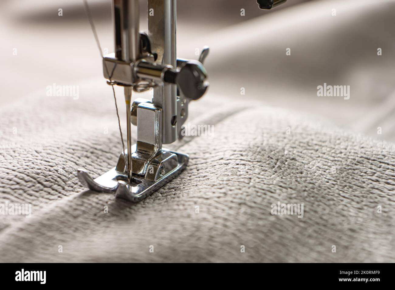 Machine à coudre moderne presser le pied avec tissu et fil gris, gros plan, espace de copie. Processus de couture vêtements, rideaux, tissus d'ameublement. Affaires, loisirs, ha Banque D'Images