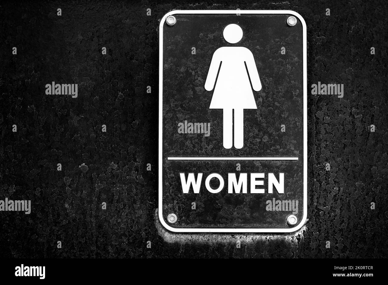 Affiche de toilettes pour femmes sur la porte noire avec des taches noires et blanches Banque D'Images