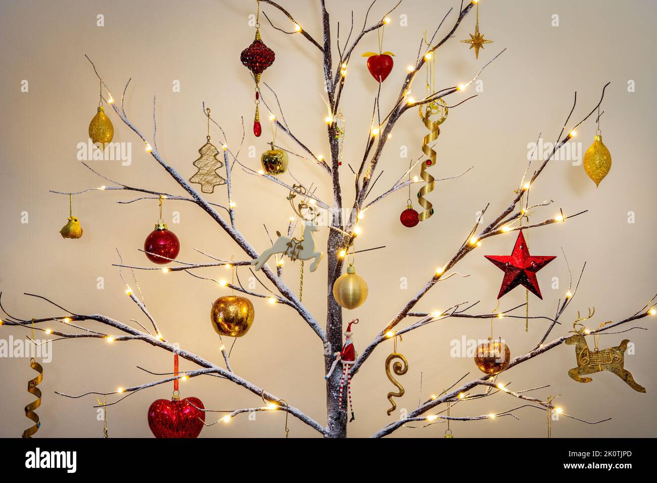 Décorations de Noël en rouge et or traditionnel accrochées à un arbre perruque moderne avec effet neige Banque D'Images
