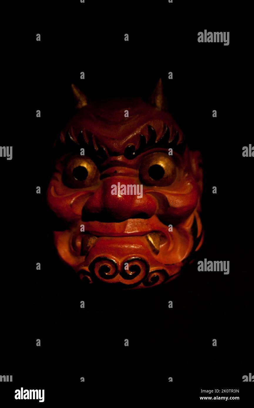 Un cliché vertical d'un masque d'oni japonais utilisé dans le théâtre de Noh isolé sur fond noir Banque D'Images