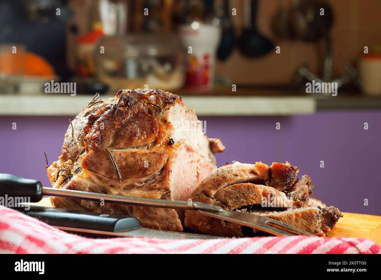 Viande de porc cuite avec épices tranchées sur une planche à découper brune avec couteau et fourchette. Banque D'Images