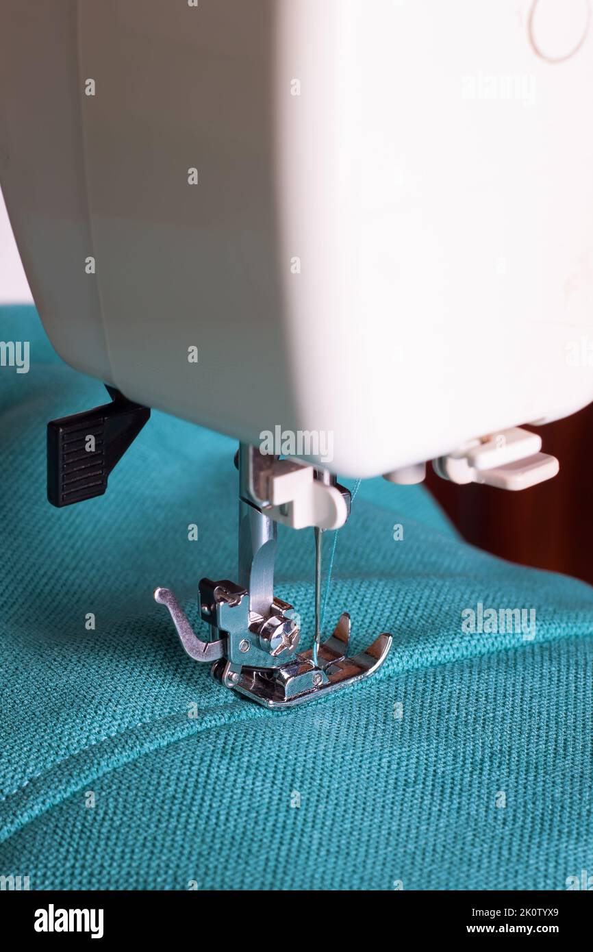 Machine à coudre moderne en tissu turquoise. Processus de couture. Banque D'Images