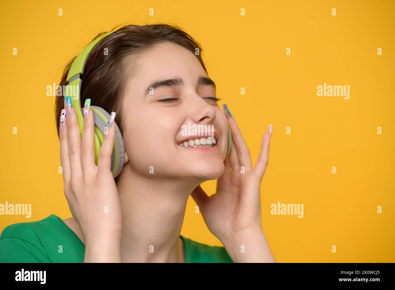 Jeune belle brunette avec une coupe courte aime écouter de la musique sur des écouteurs sans fil Banque D'Images