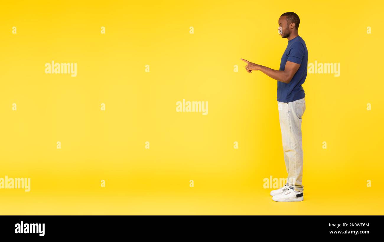 L'homme noir pointe le doigt vers l'espace de copie, arrière-plan jaune Banque D'Images