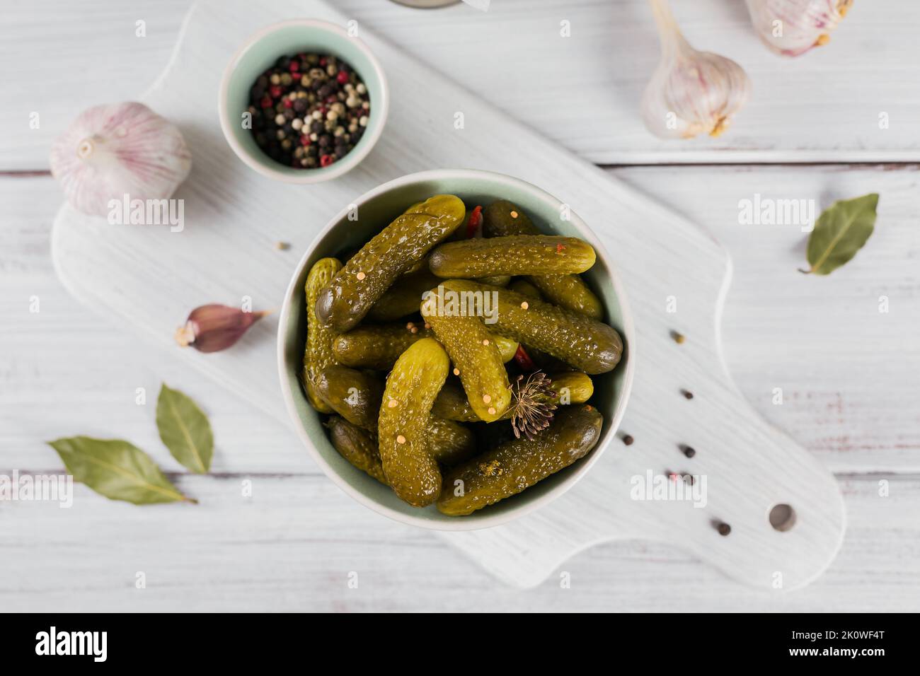 Conserver les concombres marinés, les assaisonnements et l'ail sur une table en bois blanc. Aliments fermentés sains. Légumes en conserve à la maison. Banque D'Images