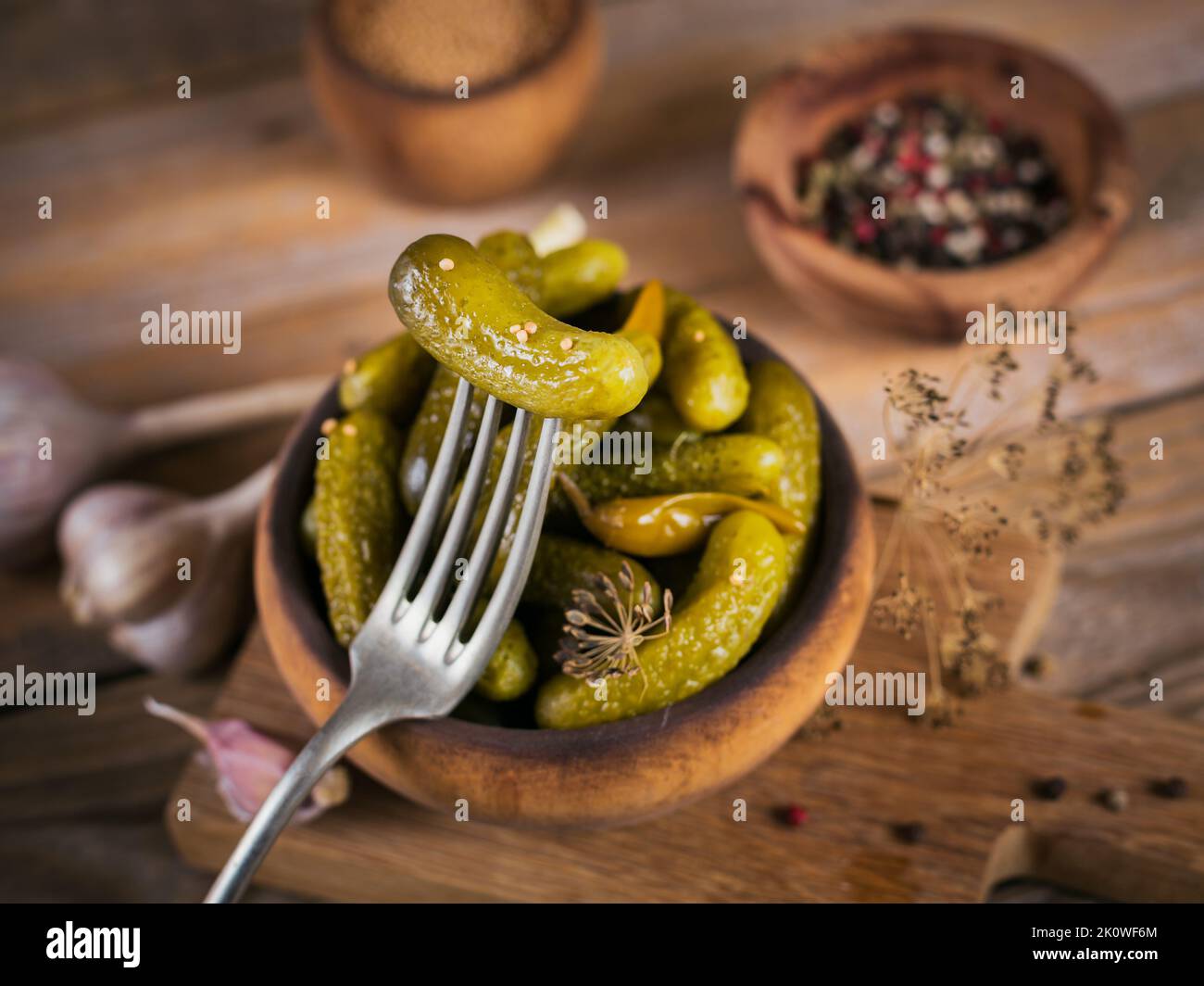 Cornichons, concombre mariné sur une fourchette, bol de légumes marinés sur un fond rustique en bois. Cuisine propre, concept végétarien Banque D'Images