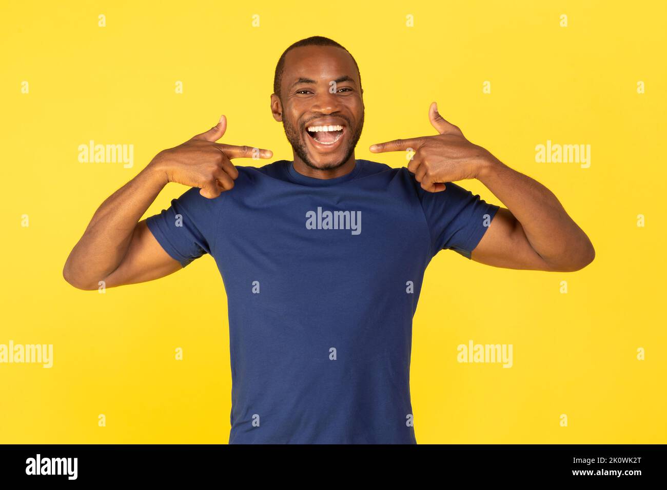 Guy noir pointant les doigts vers le sourire craquant sur fond jaune Banque D'Images