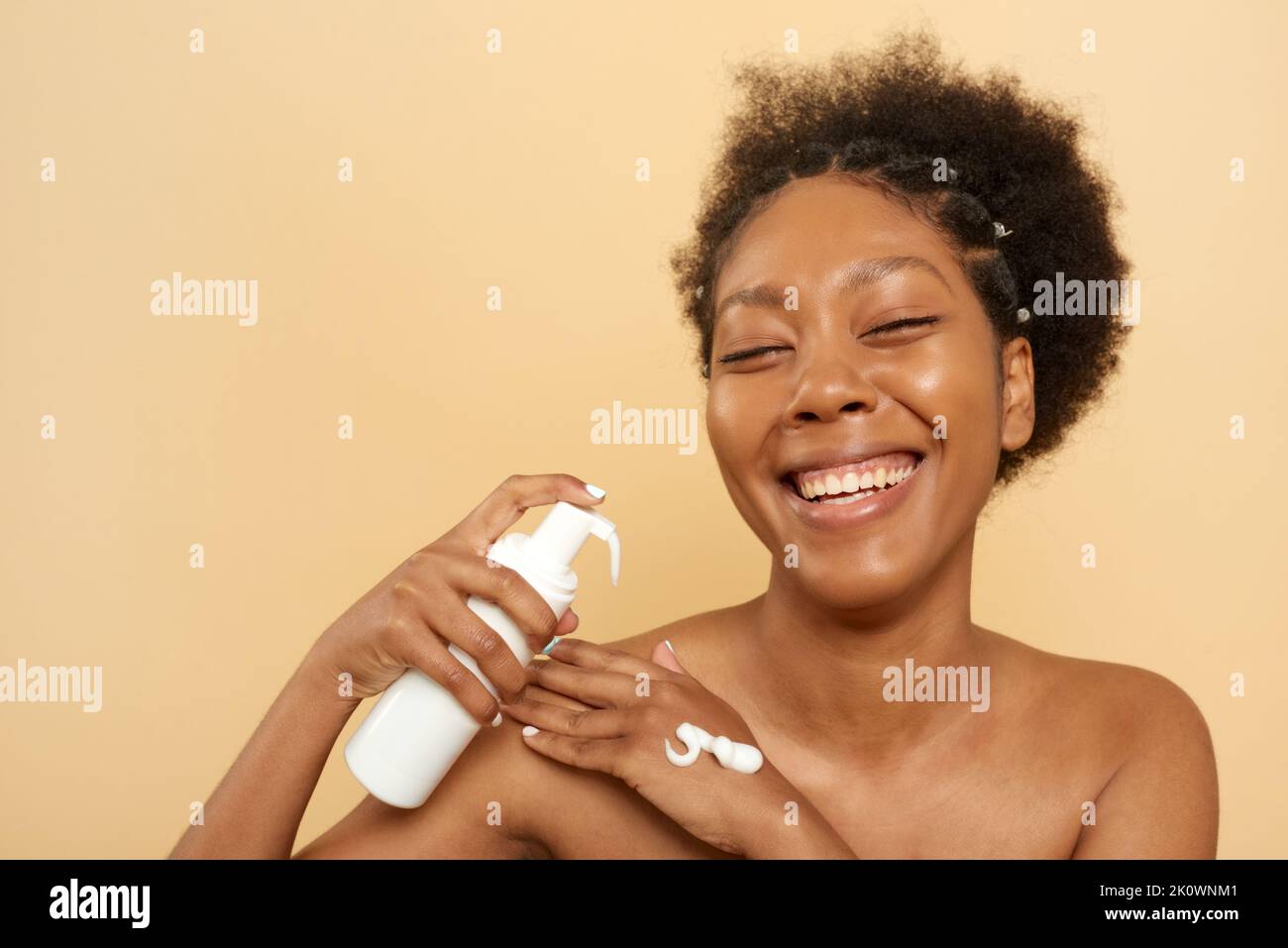 Femme afro-américaine joyeuse avec bouteille de mousse nettoyante en studio Banque D'Images