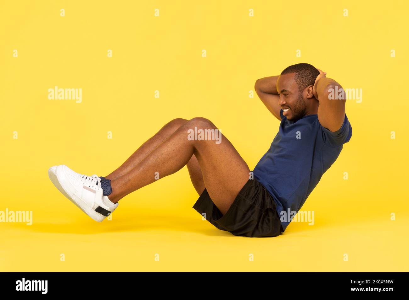 African American Man Doing Sit UPS exercice sur fond jaune Banque D'Images