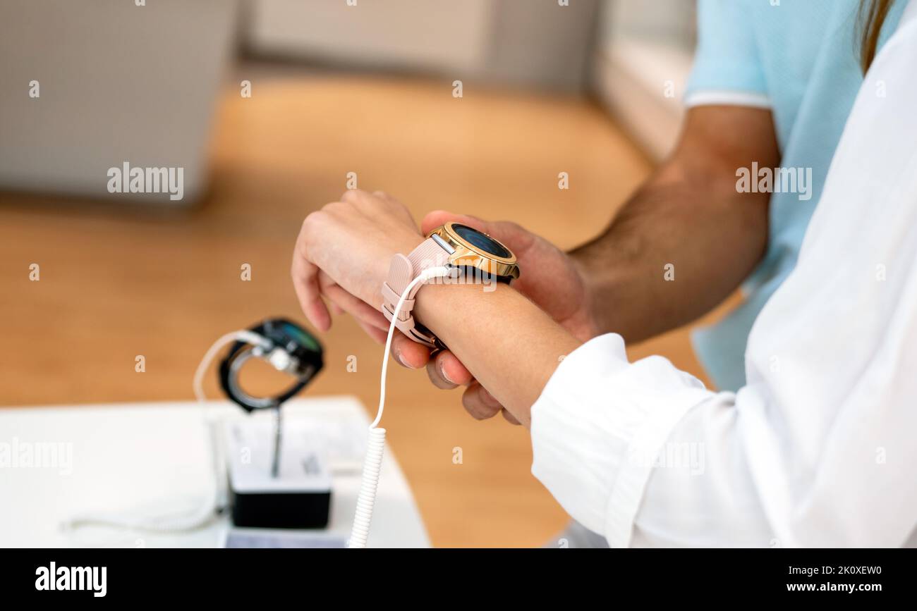 Portrait d'une femme souriante et heureuse qui magasinent une nouvelle montre intelligente dans un magasin de technologie.Concept de personnel technologique Banque D'Images