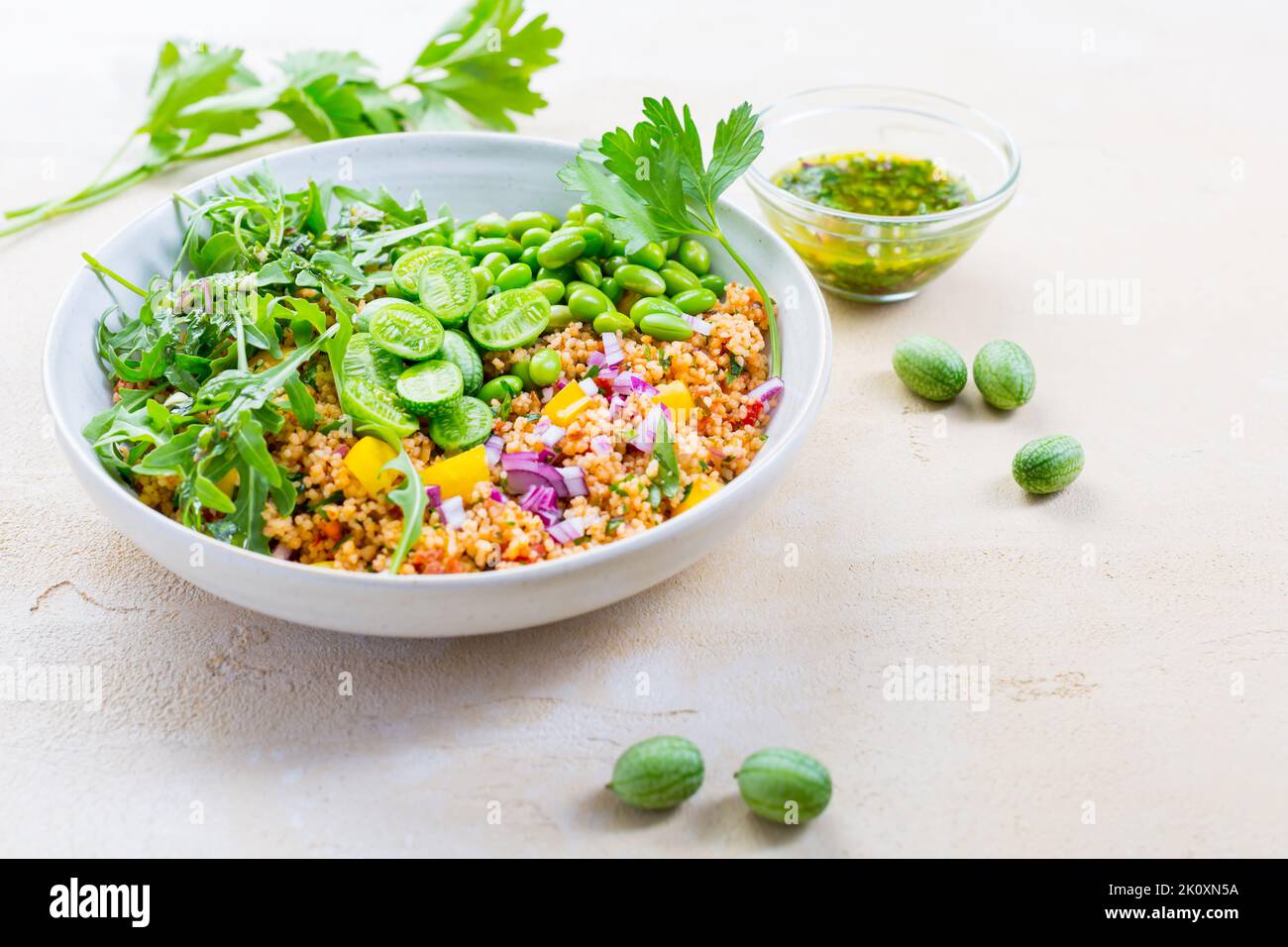 Salade de couscous saine avec haricots édamames, rucola et cucamelon (pastèque mexicaine miniature), avec sauce citron et herbes Banque D'Images