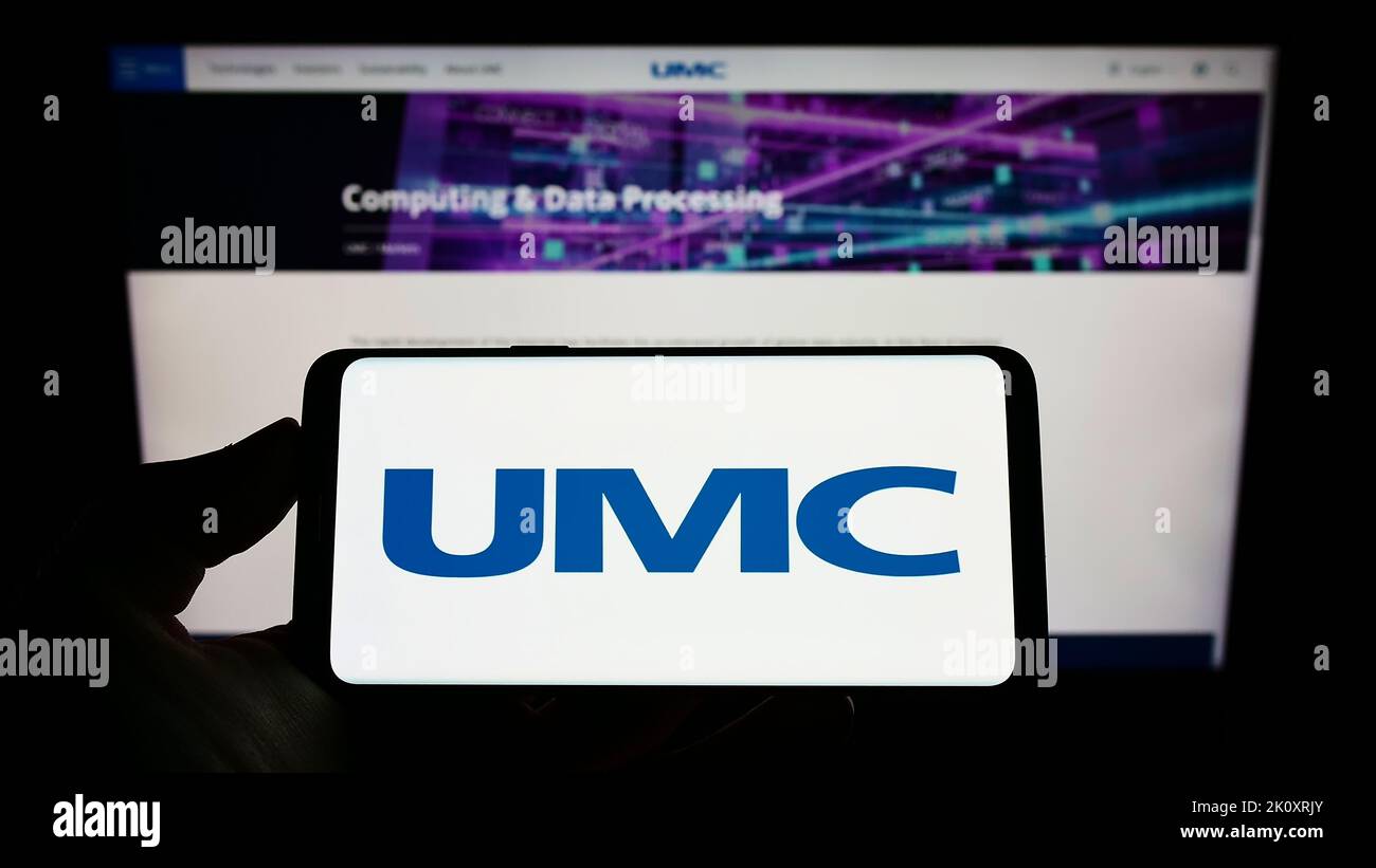 Personne tenant un téléphone portable avec le logo de la société United Microelectronics Corporation (UMC) à l'écran devant la page Web. Mise au point sur l'affichage du téléphone. Banque D'Images