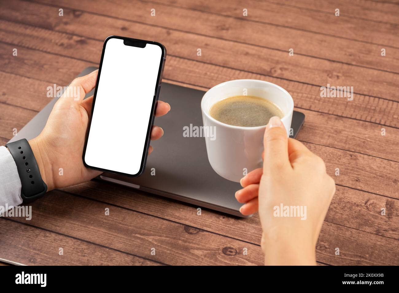 Tenir le smartphone, photo rapprochée d'une femme tenant le smartphone. Une femme fait une pause pour prendre un café frais, ferme son ordinateur portable et ses messages. Banque D'Images