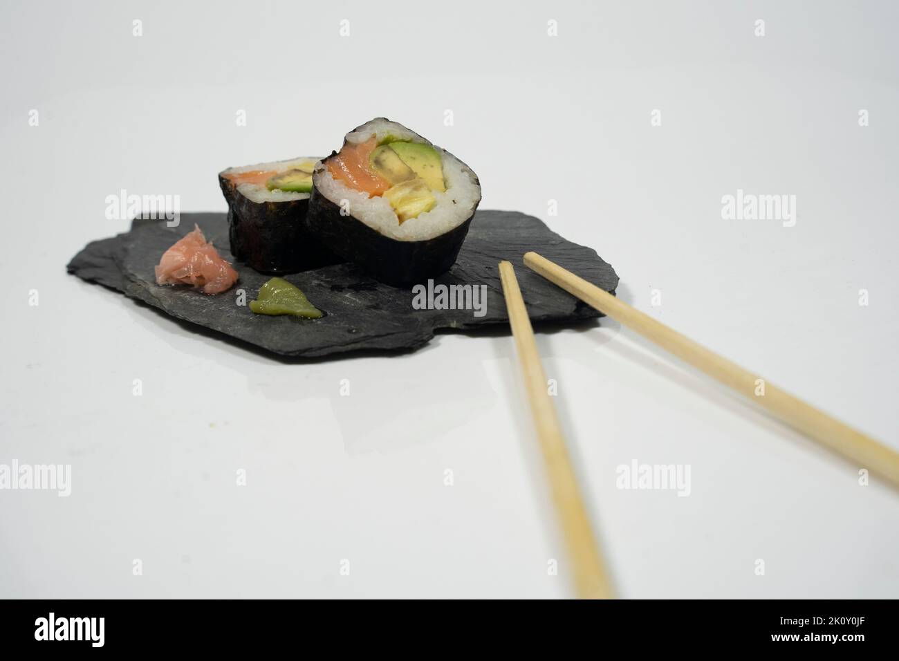 deux morceaux de sushi dans une assiette de tableau noir avec un bâton, du gingembre et du wasabi Banque D'Images