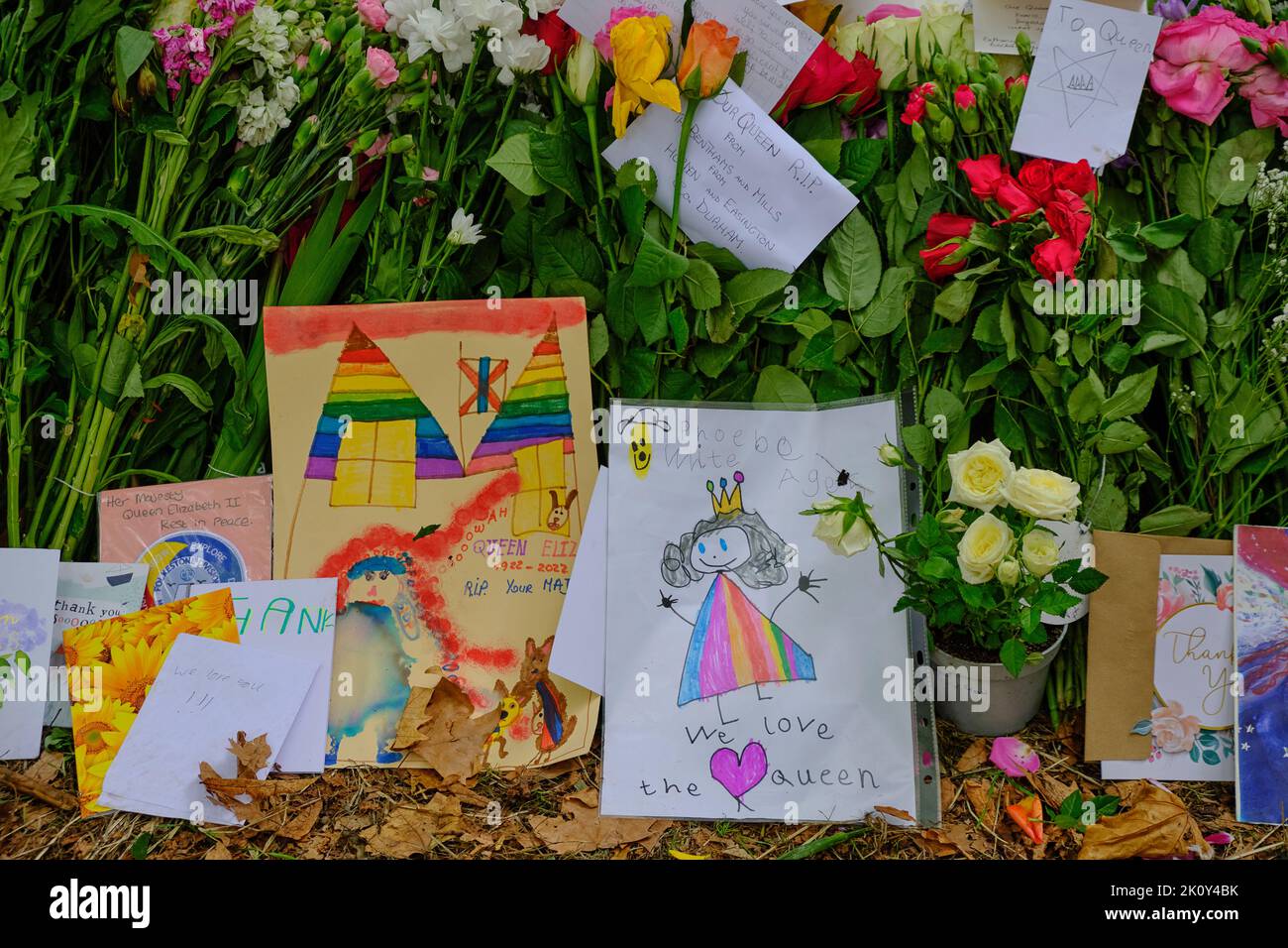 Les enfants apportent des cartes et des photos dessinées à la main dans le cadre d'un hommage floral après la mort de la Reine, Green Park, Londres Banque D'Images