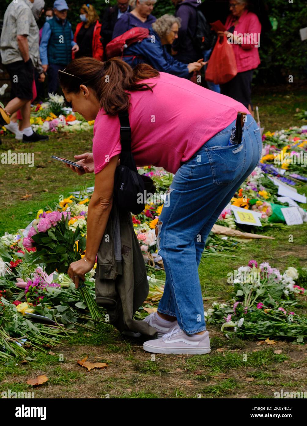 Femme pose des fleurs dans le cadre d'un hommage floral après la mort de la Reine, Green Park, Londres Banque D'Images
