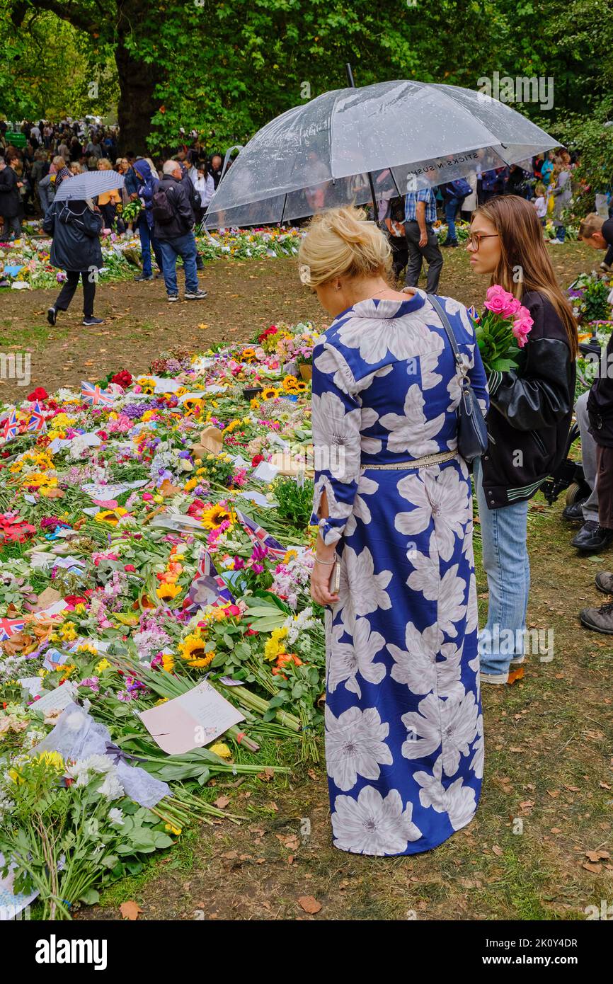 Femme en robe fleurie apporte des fleurs dans le cadre d'un hommage floral après la mort de la Reine, Green Park, Londres Banque D'Images