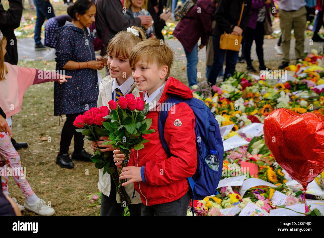 Les enfants apportent des fleurs dans le cadre d'un hommage floral après la mort de la Reine, Green Park, Londres Banque D'Images