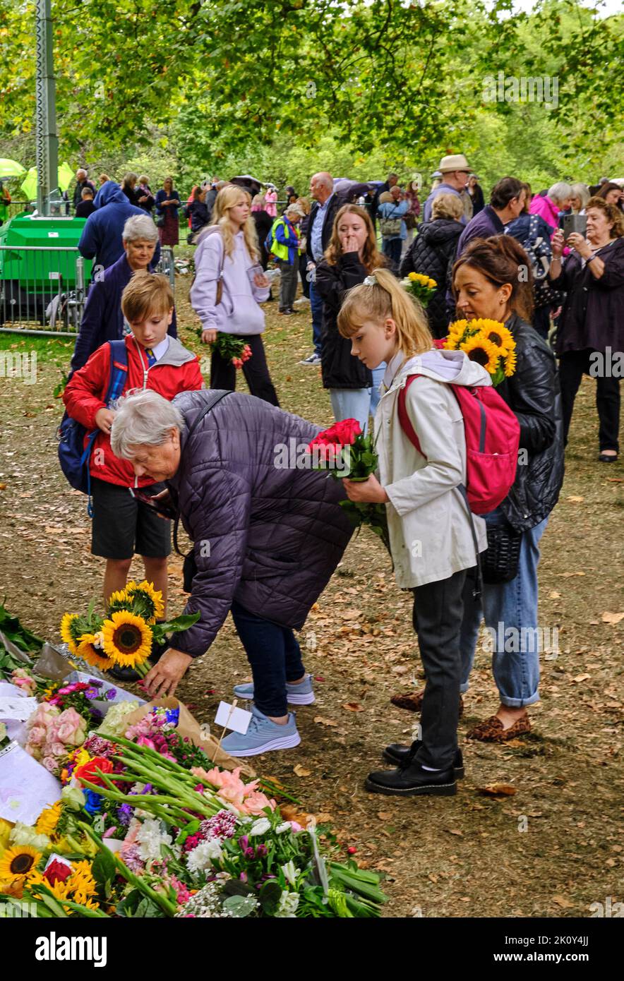 La famille apporte leurs enfants pendant la pause-déjeuner scolaire pour déposer des fleurs à Green Park après le décès de la Reine Banque D'Images