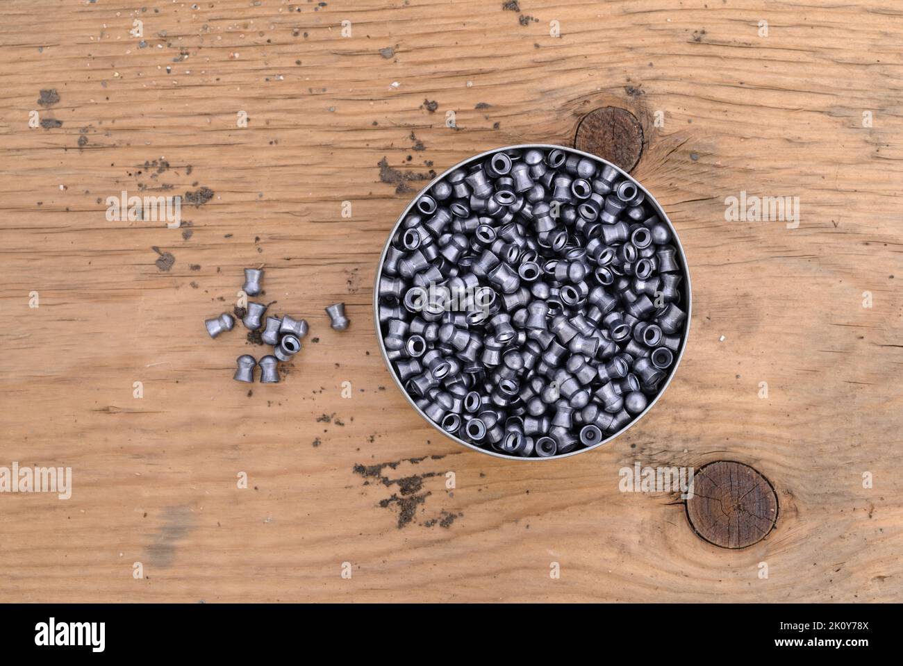 Vue de dessus d'une boîte ouverte de pellets de pistolet à air sur un vieux panneau de bois avec plusieurs pellets sur le côté. Banque D'Images