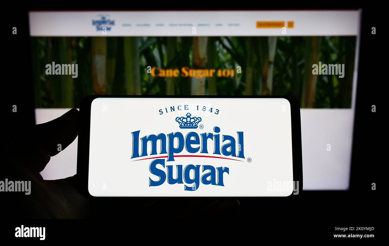 Personne tenant un smartphone avec le logo du producteur américain de sucre Imperial Sugar Company à l'écran devant le site Web. Mise au point sur l'affichage du téléphone. Banque D'Images