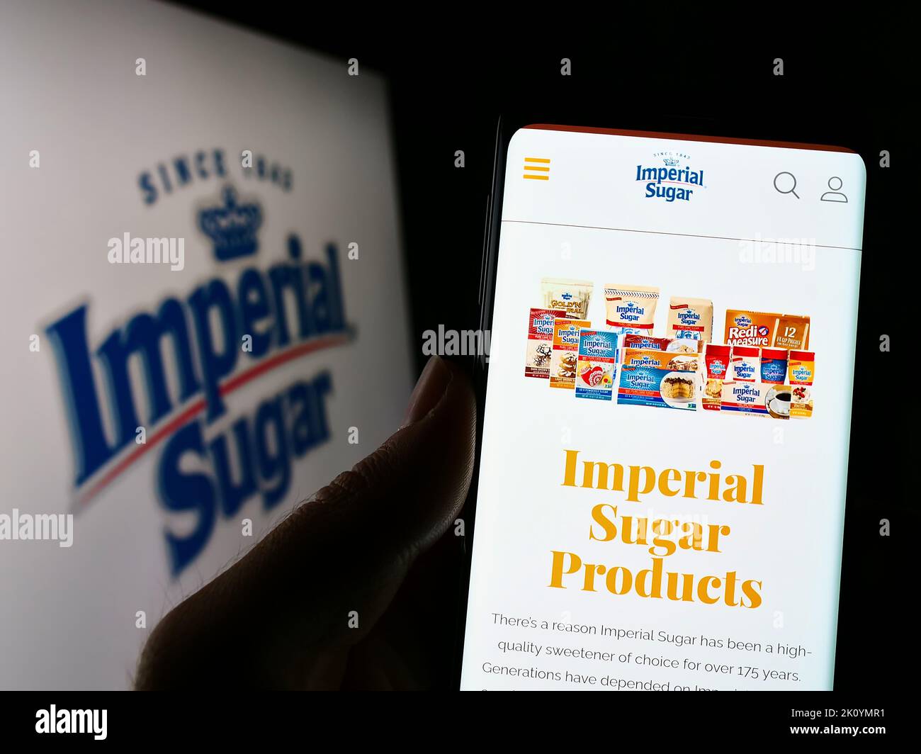 Personne tenant un téléphone cellulaire avec le site Web du producteur américain de sucre Imperial Sugar Company à l'écran devant le logo. Concentrez-vous sur le centre de l'écran du téléphone. Banque D'Images