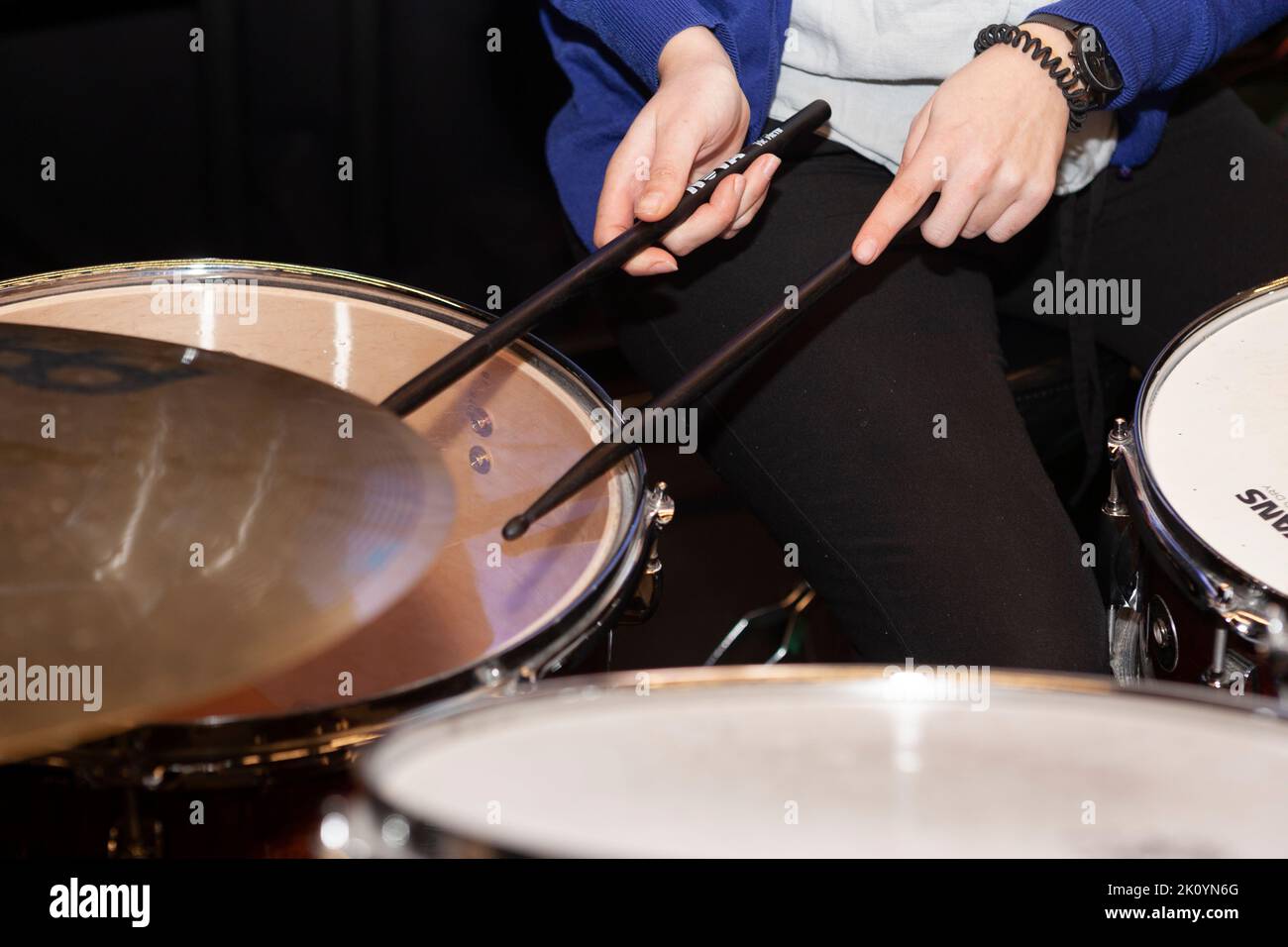 Gros plan d'une paire de mains de musicien tenant des pilons de tambour tout en jouant un tambour d'arracher dans un orchestre amateur Banque D'Images