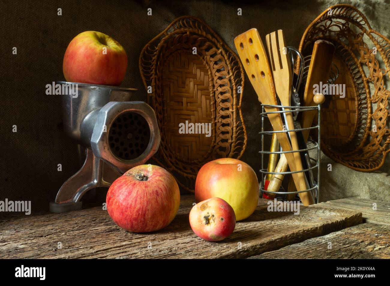 Pommes mûres avec ustensiles de cuisine. Fruit avec un moulin à viande sur une table en bois ancienne Banque D'Images