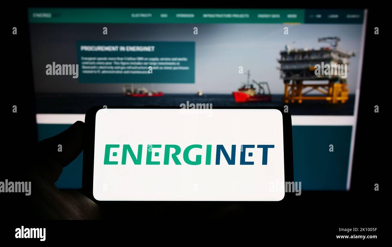 Personne tenant un smartphone avec le logo de l'opérateur danois du système de transmission Energinet à l'écran devant le site Web. Mise au point sur l'affichage du téléphone. Banque D'Images