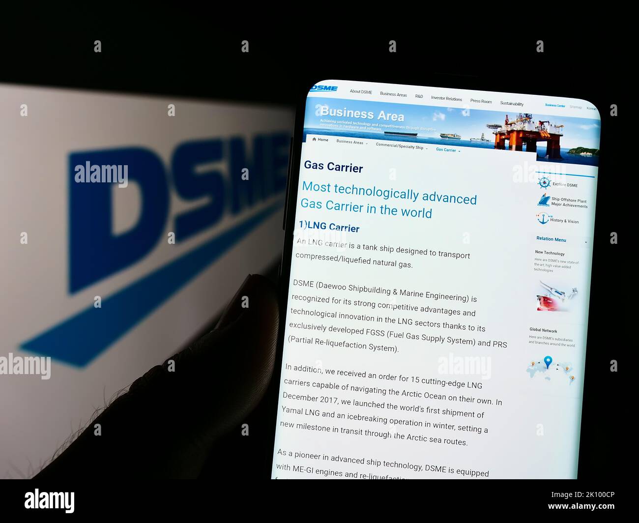 Personne tenant le téléphone portable avec la page web de Daewoo Shipbuilding and Marine Engineering (DGME) à l'écran avec le logo. Concentrez-vous sur le centre de l'écran du téléphone. Banque D'Images