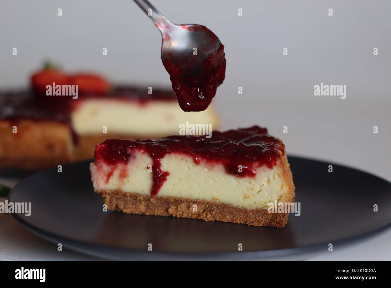 Tranche de gâteau au fromage fraise. Gâteau au fromage soyeux doux et crémeux recouvert d'une sauce aux fraises maison. Prendre avec des fraises fraîches autour Banque D'Images