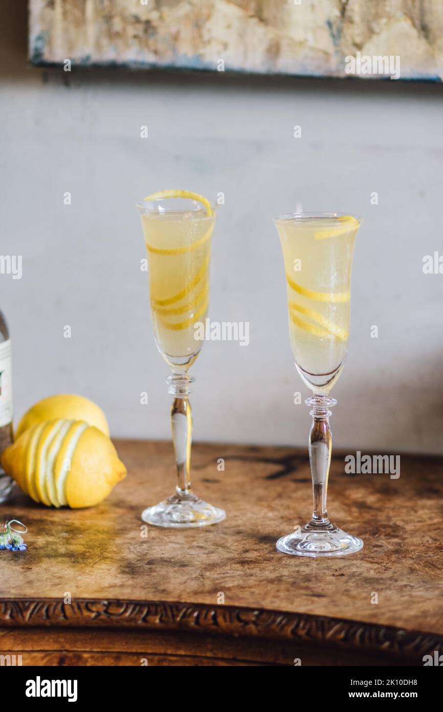 Deux flûtes à champagne avec un cocktail français 75 et de longues branches de citron Banque D'Images