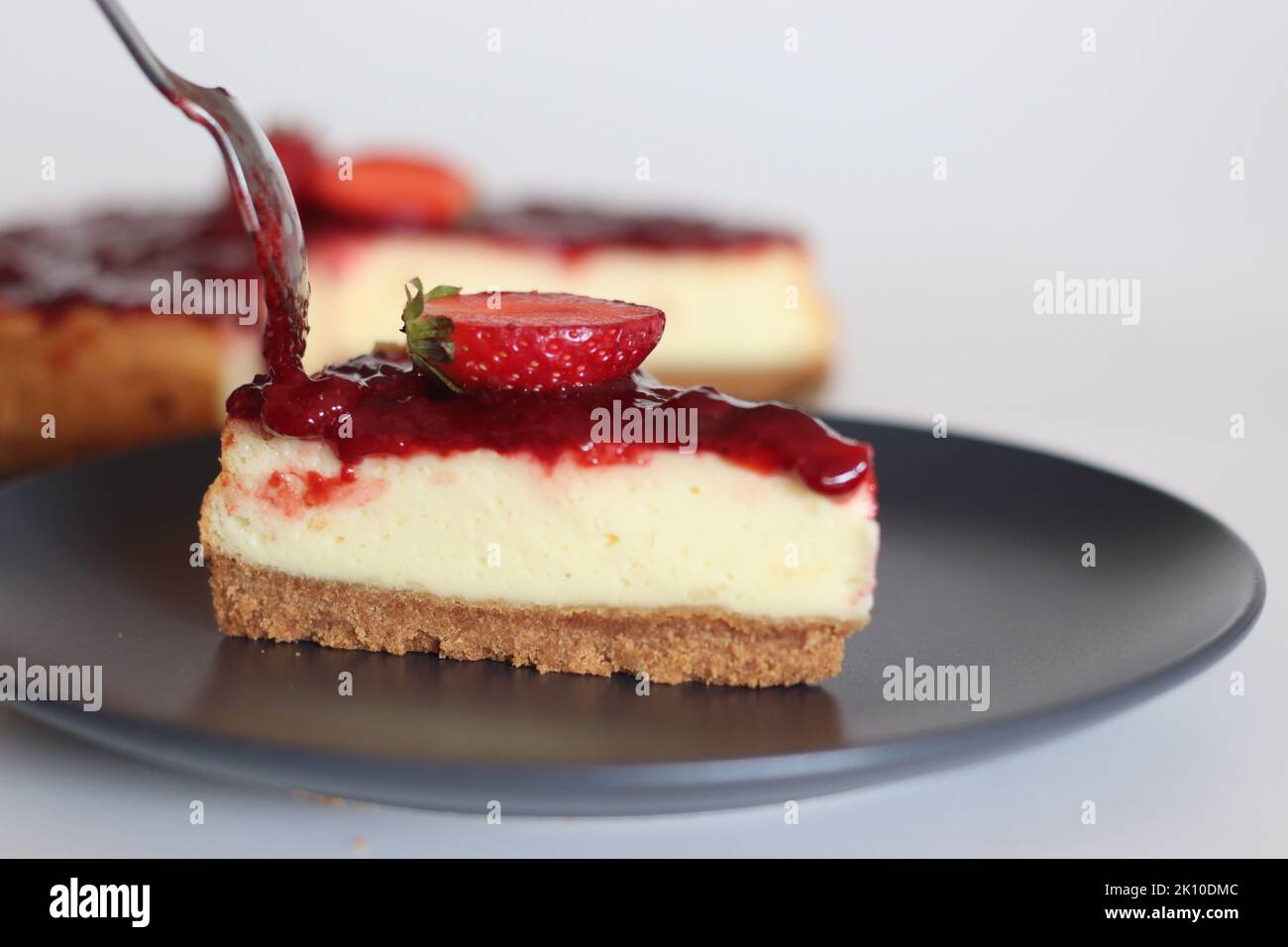 Tranche de gâteau au fromage fraise. Gâteau au fromage soyeux doux et crémeux recouvert d'une sauce aux fraises maison. Prendre avec des fraises fraîches autour Banque D'Images