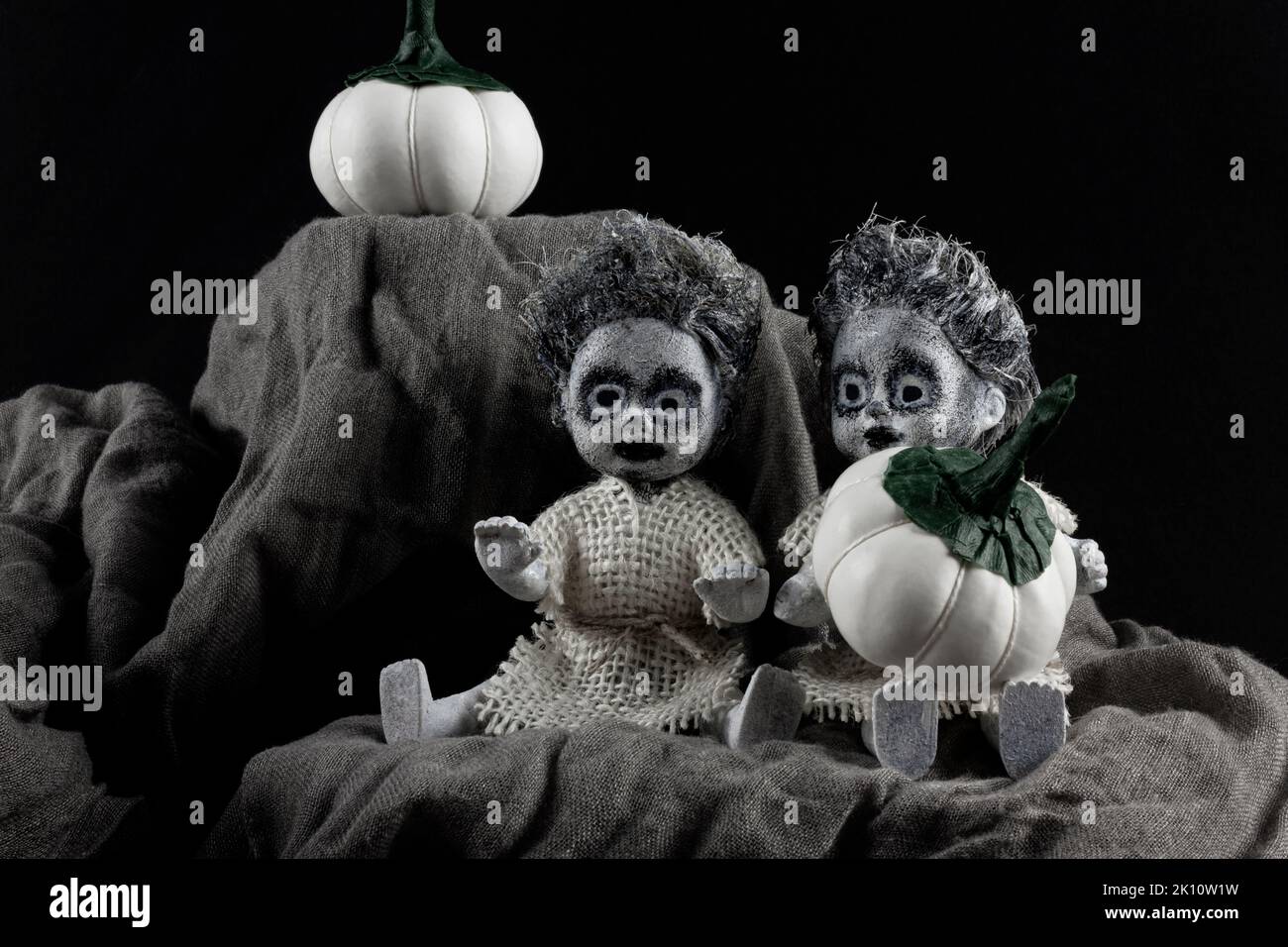 Joyeuses fêtes d'Halloween. Deux poupées zombies effrayantes avec citrouilles blanches sur fond sombre. Banque D'Images