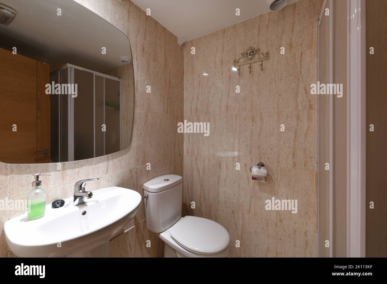 Salle de bains avec miroir sans cadre, lavabo sur pied en porcelaine blanche et carrelage en marbre Banque D'Images