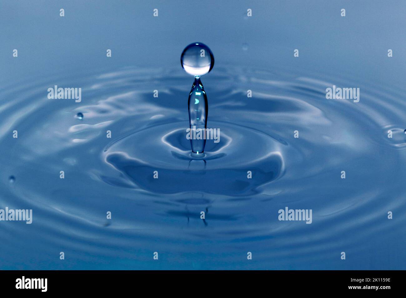 Une goutte tombe dans l'eau et crée de grandes formes Banque D'Images