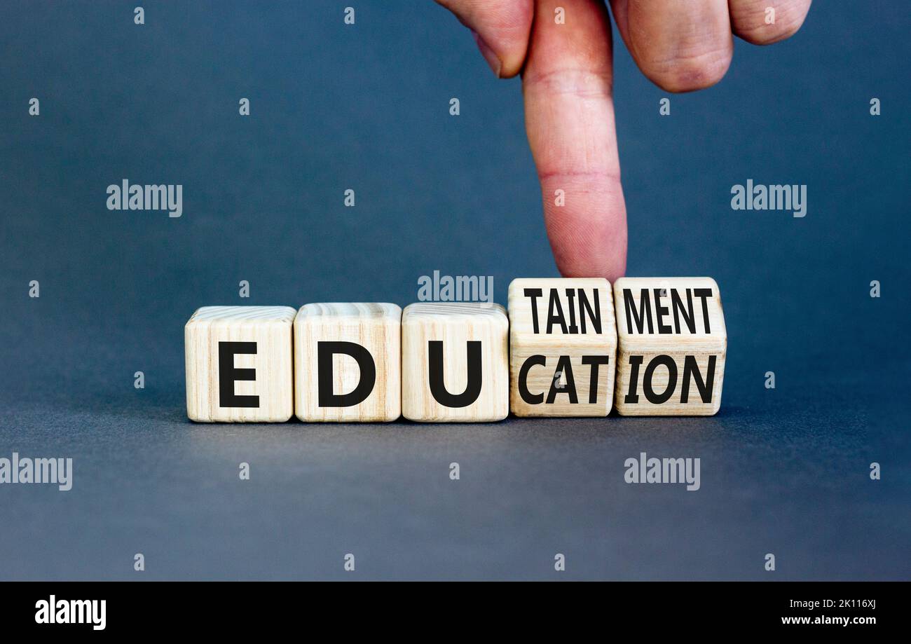 Symbole éducation et divertissement. Concept Words Education et edutainment sur des cubes en bois. Main du professeur. Magnifique fond gris de table. Educati Banque D'Images