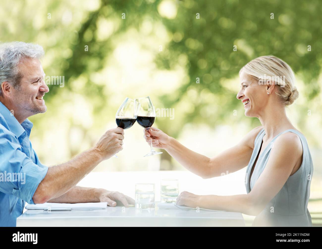 Heres à notre bonheur et à notre amour continus. Couple d'âge mûr heureux en dégustant leur amour avec deux verres de vin pendant qu'ils sont à l'extérieur. Banque D'Images