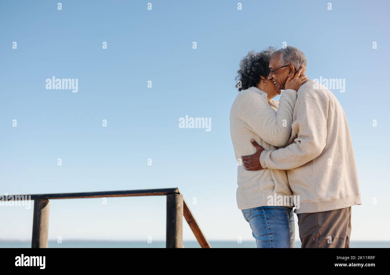 Les oiseaux de rivage mûrs étant romantiques à la plage. Heureux couple senior s'embrassant en se tenant sur un pont de pied en bois. Couple de personnes âgées à la retraite Banque D'Images