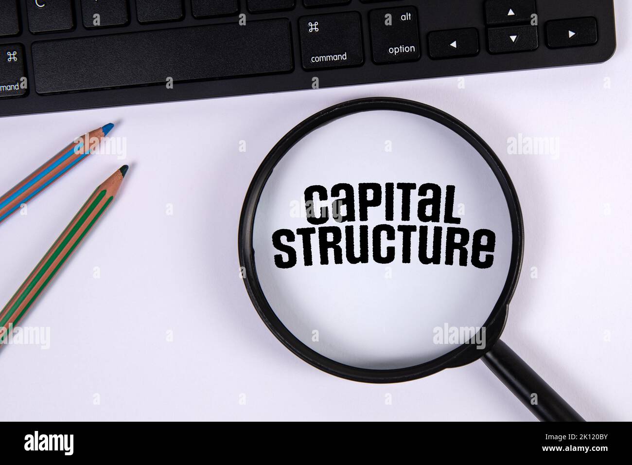 Structure du capital. Clavier de l'ordinateur et loupe sur fond blanc. Banque D'Images