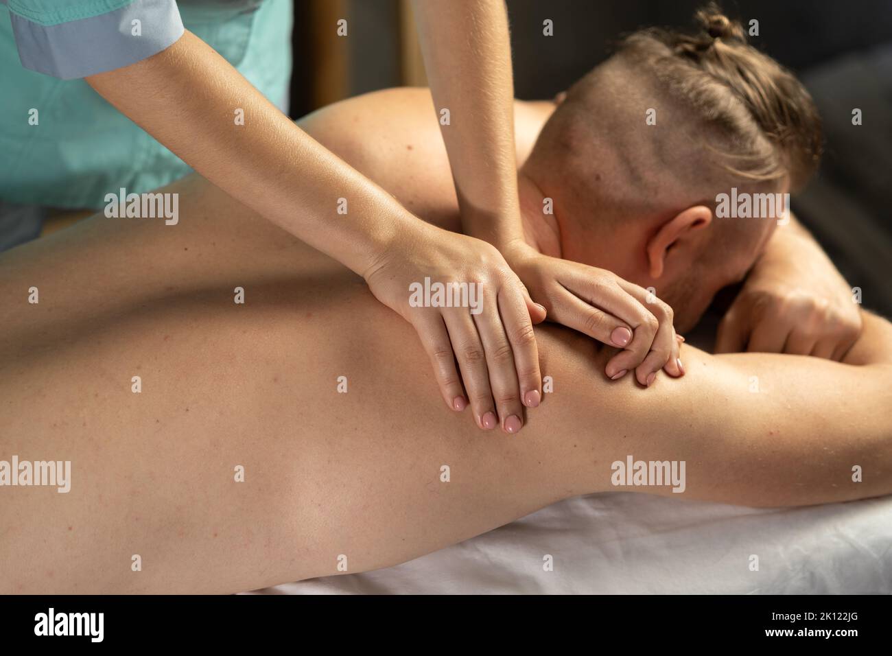 Jeune homme caucasien se détendre pendant le massage sur le dos. Homme assistant au spa masculin moderne, s'allonger sur la table de massage, obtenant la procédure de guérison du corps. Banque D'Images