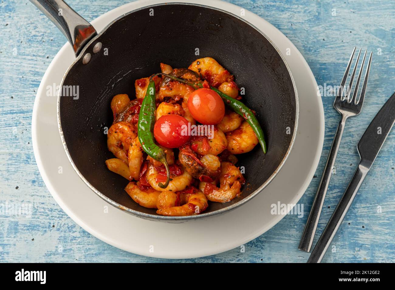 Cocotte de crevettes avec tomates, ail et poivrons dans un wok noir Banque D'Images