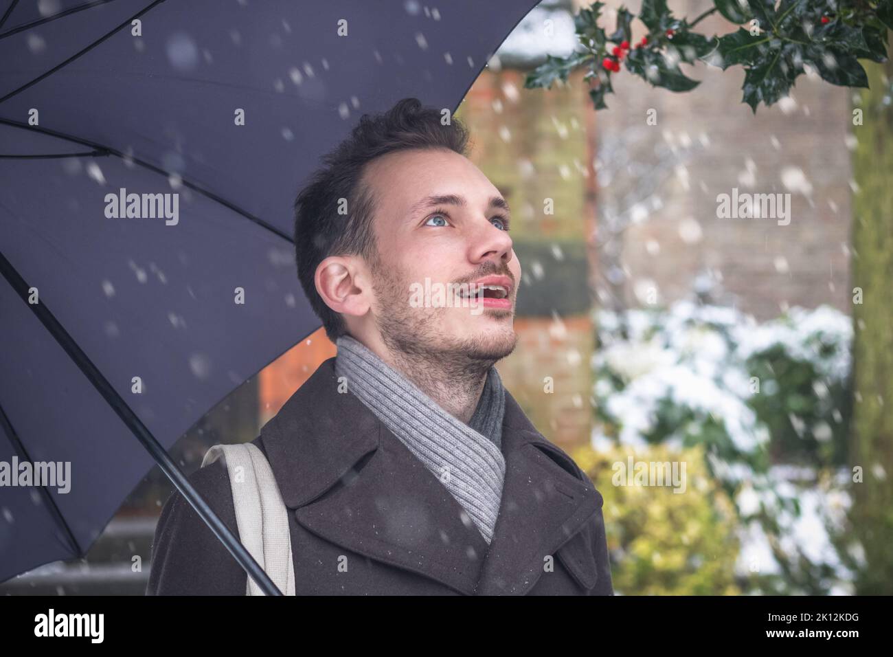 Portrait d'un beau jeune homme avec parapluie en hiver neige Banque D'Images