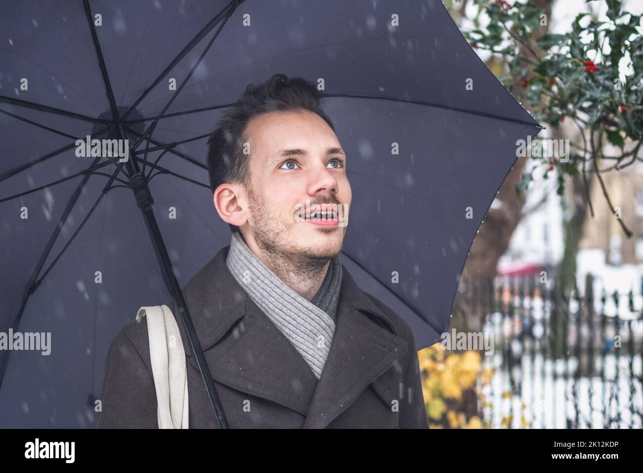 Portrait d'un beau jeune homme avec parapluie en hiver neige Banque D'Images