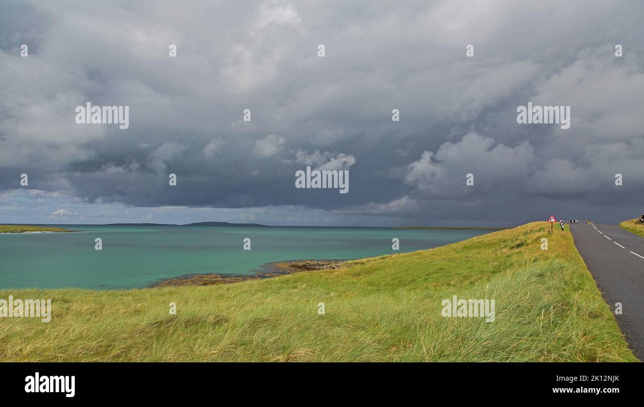 Thunder Clouds sur Sunny Road à côté de la mer, Uist, Uist Nord, Hébrides, Hébrides extérieures, Îles de l'Ouest, Ecosse, Royaume-Uni, Grande-Bretagne, Banque D'Images