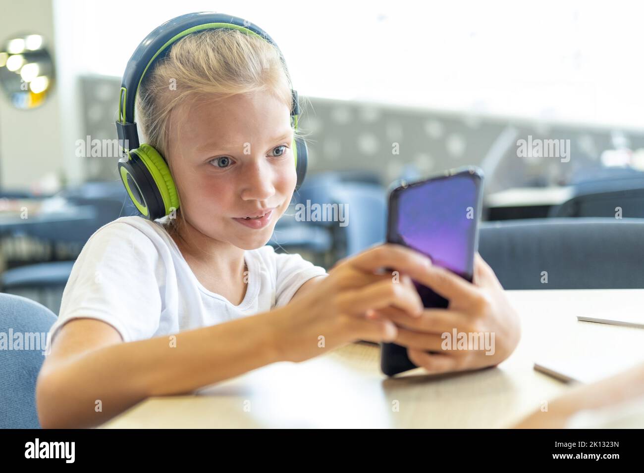 Une petite fille avec un casque regarde des dessins animés sur son
