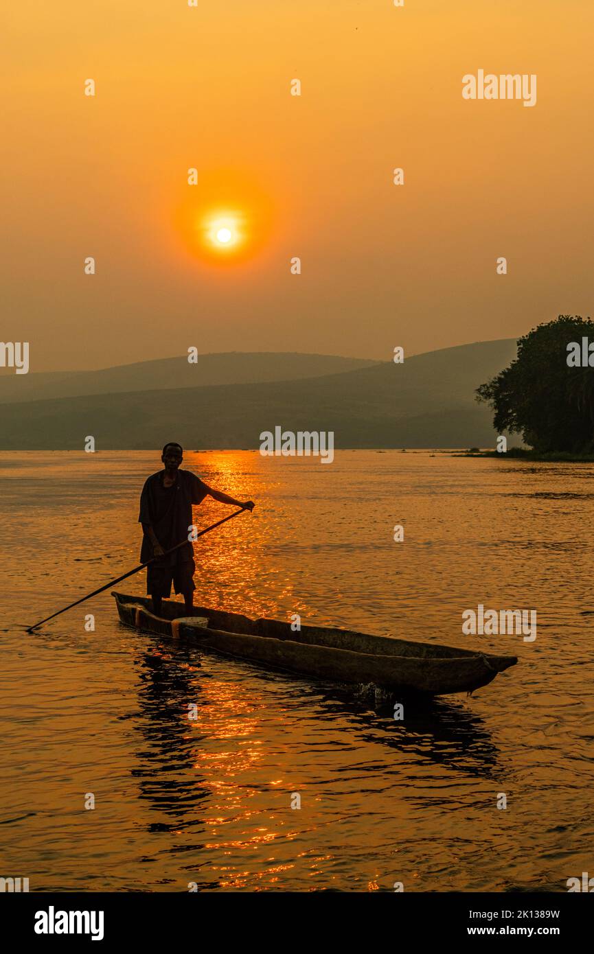 Homme sur son canot de dugout au coucher du soleil sur le fleuve Congo, République démocratique du Congo, Afrique Banque D'Images