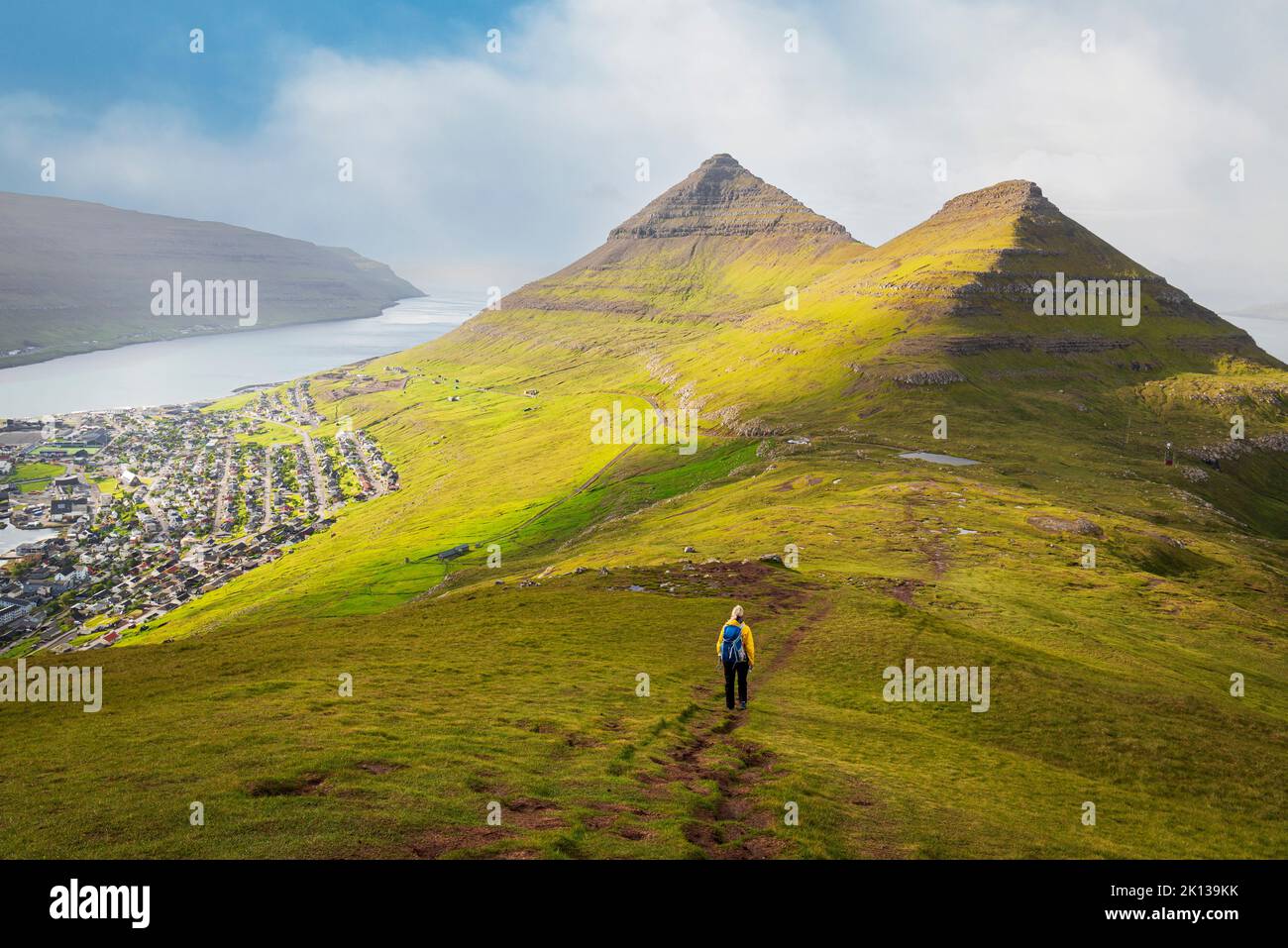 Randonneur avec veste jaune descend le mont Klakker, Klaksvik, île Borooy, îles Féroé, Danemark, Europe Banque D'Images